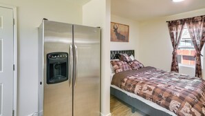 A bedroom with a large bed, a refrigerator, and a water dispenser. - Studio 2 Mi to Feather River: Bring Your Pet! (Oroville)