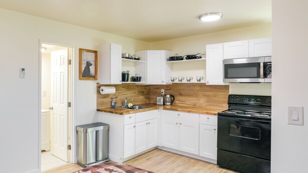 A compact kitchen with white cabinets, a black stove, and a microwave. - Studio 2 Mi to Feather River: Bring Your Pet! (Oroville)