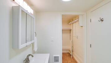A bathroom with a sink, mirror, and shower area.