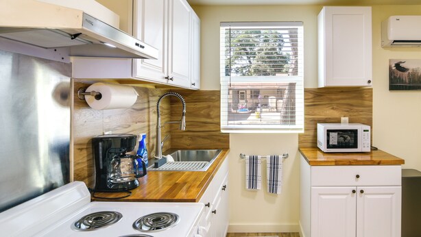 A compact kitchen with a stove, sink, and microwave, wooden countertops, and a window with a view. - 2 Mi to Feather River: Outdoor Escape in Oroville! (Oroville)