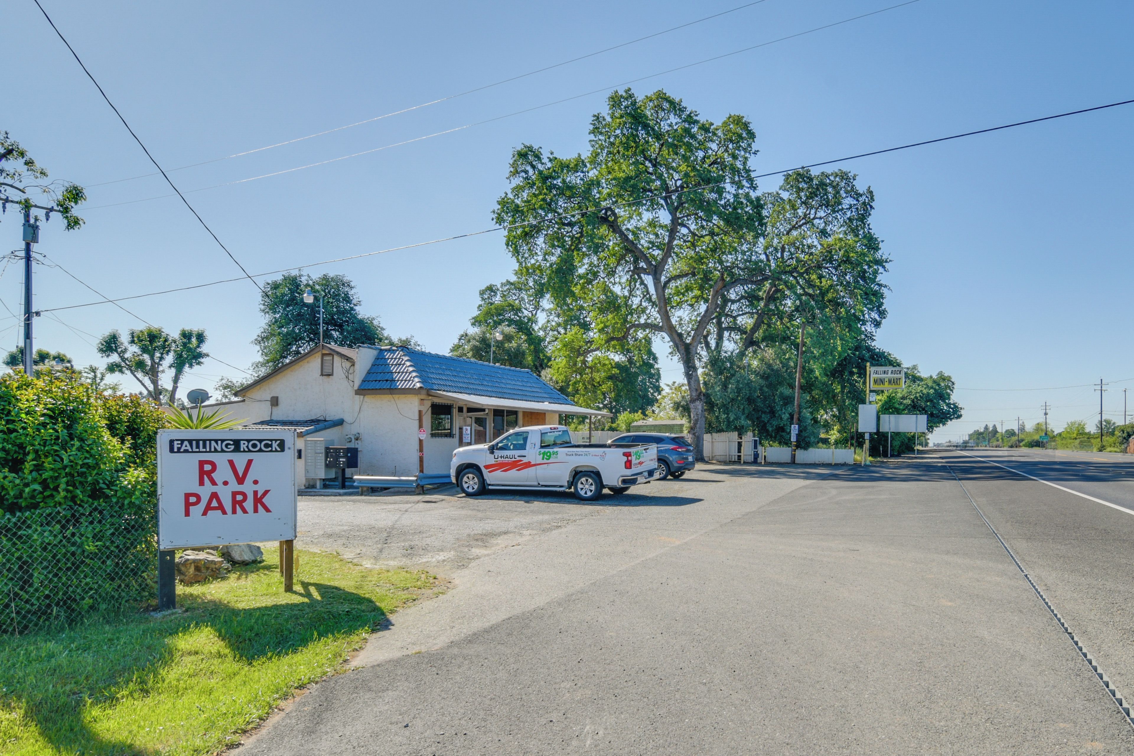 A parking area with a sign for Falling Rock RV Park, a small building, and a parked truck.