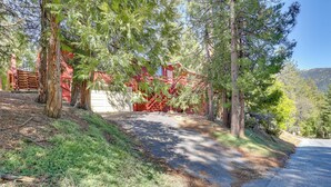 A red building with a garage, surrounded by trees and a dirt path. - Across From Hiking Trails: Woodsy Studio! (Idyllwild)