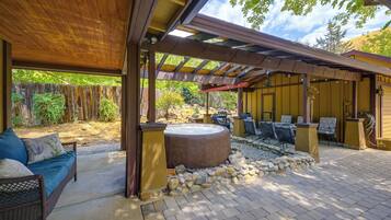 Un patio exterior con zona de estar techada, jacuzzi y detalles de piedra.