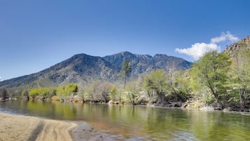 A river with clear water, surrounded by mountains and sparse vegetation.