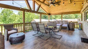 A covered outdoor patio with wooden flooring, wicker furniture, and a ceiling fan. - Deck & Yard: 'margy's Farmhouse' in Jasper (Jasper)