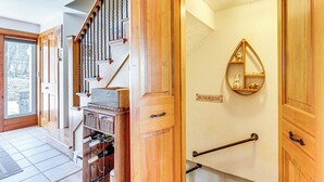 Una scala in legno con corrimano, uno scaffale a parete con oggetti decorativi e una porta con la scritta "BUNKHOUSE".