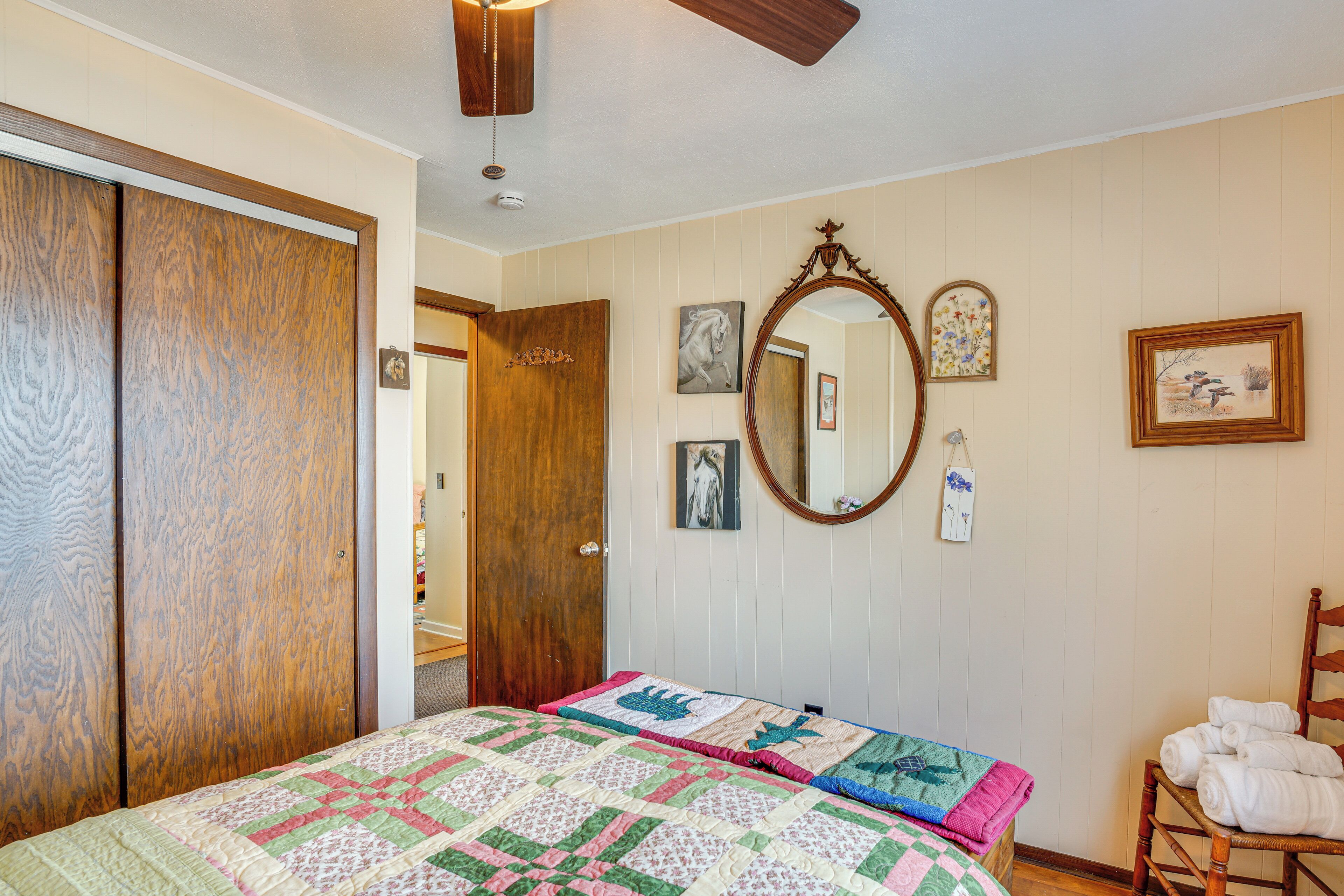 Un dormitorio con cama, un armario de madera, un espejo y una silla con toallas.