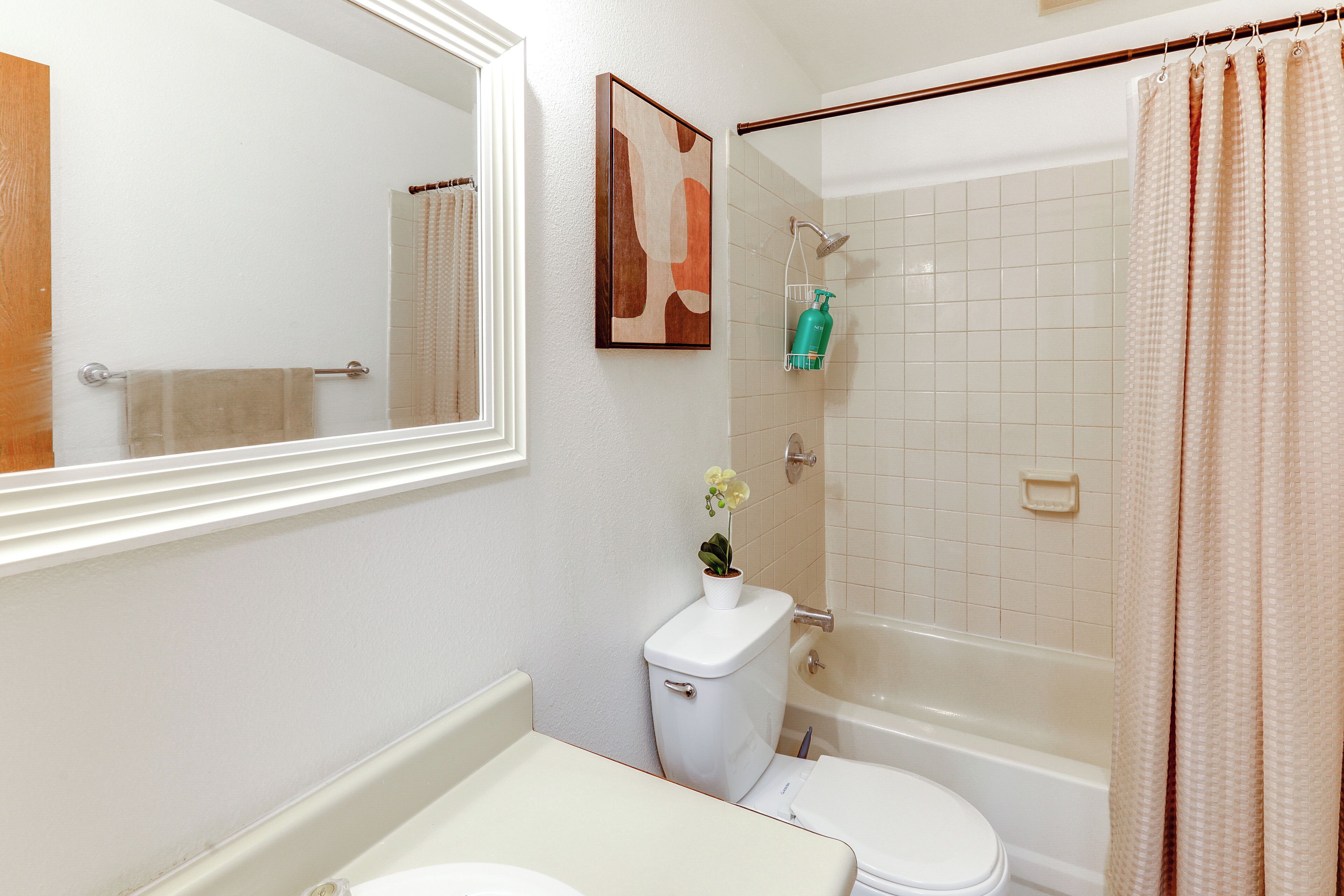 Un baño con inodoro, lavamanos, espejo, ducha y toallero.
