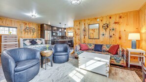 Un salon chaleureux avec un canapé, deux fauteuils, une table basse et un coin repas comprenant une table et des chaises.