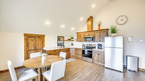 A modern kitchen with wooden cabinets, a dining table with chairs, a microwave, an oven, and a refrigerator. - Balcony & Patio w/ Mtn Views! Bonners Ferry Escape (Bonners Ferry)