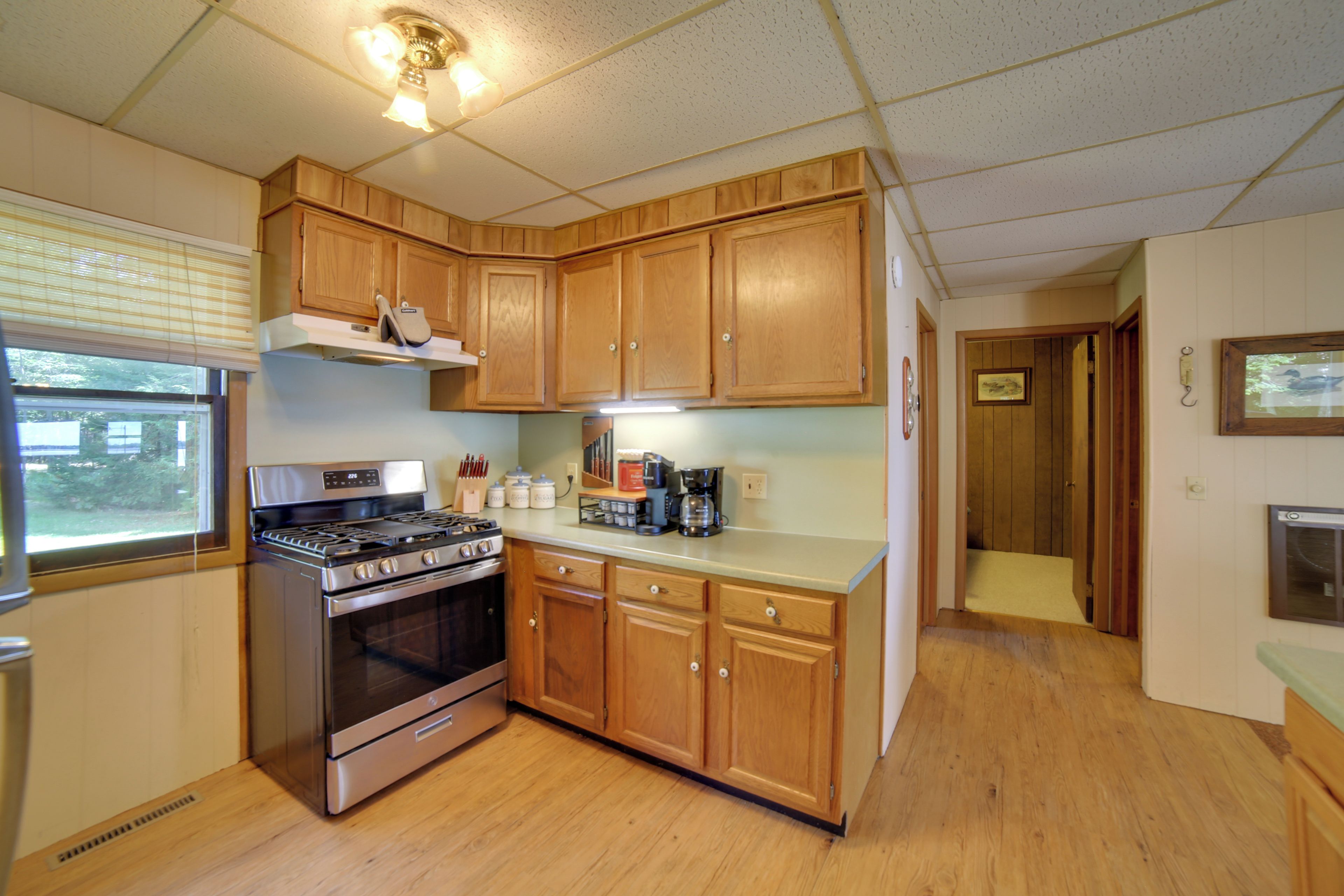 A kitchen with wooden cabinets, a stove, and a window.
