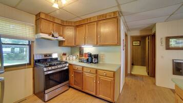 A kitchen with wooden cabinets, a stove, and a window.