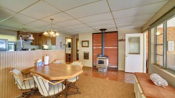 A kitchen with a dining table and chairs, a stove, and a window with blinds.