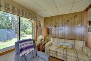 Une pièce avec une fenêtre, une chaise, un canapé, une lampe et des décorations murales représentant des oiseaux.