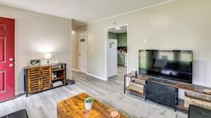 A living room with a TV, wooden coffee table, and a red door. - < 5 Mi to Dtwn Walterboro: Grill, Game & More! (Walterboro)