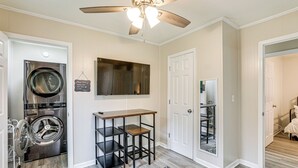 A laundry room with a washing machine, a ceiling fan, a mirror, and a small table. - < 5 Mi to Dtwn Walterboro: Grill, Game & More! (Walterboro)