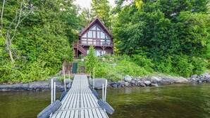 A wooden dock leading to a cabin surrounded by dense forest. - 'sweet Serenity' Schroon Lake Family Retreat! (Schroon Lake)