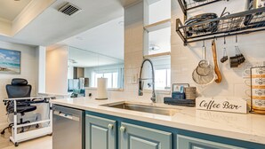 A kitchen with a coffee bar sign, a dishwasher, and a dish rack. - Steps to Ocean: Satellite Beach Condo w/ Balcony (Satellite Beach)