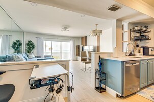 Una cocina moderna con lavavajillas, una zona de comedor con mesa y sillas, y un área de estar con sofá y plantas.