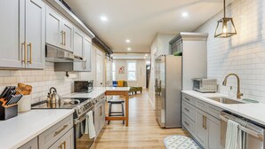 Una cucina moderna con mobili bianchi, elettrodomestici in acciaio inossidabile e un tavolo da pranzo in legno.