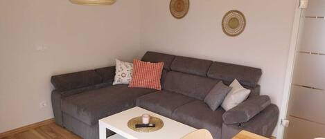 Una sala moderna con un sofá modular, una mesita blanca y una lámpara colgante.