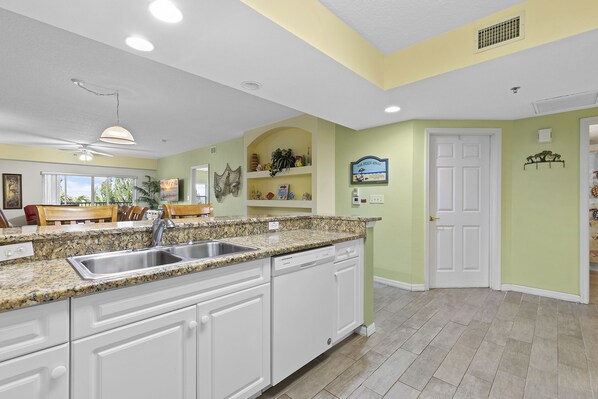 A kitchen with white cabinets, granite countertops, and a built-in dishwasher.