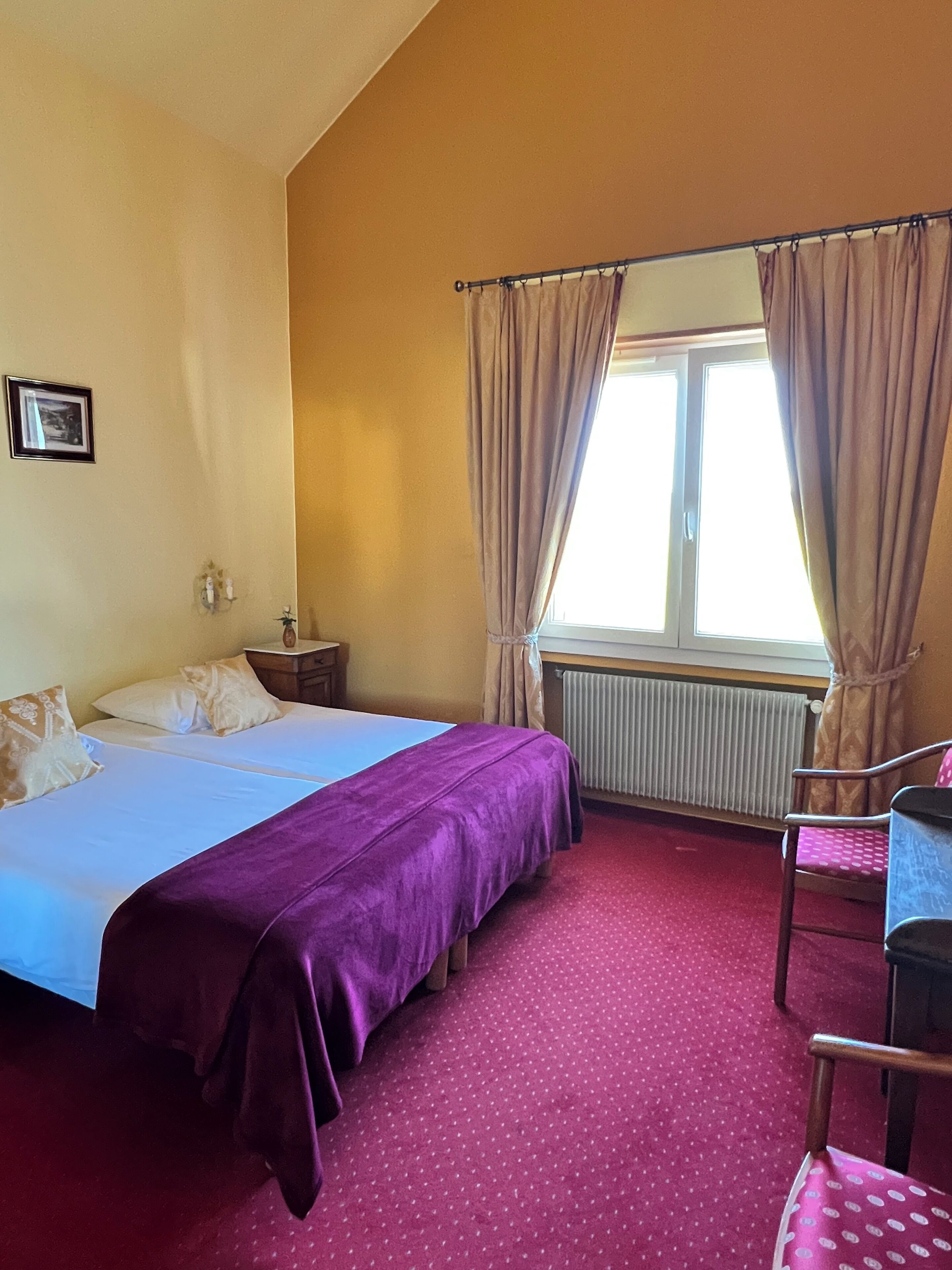 A hotel room with two beds, a desk, a chair, and a window with curtains.