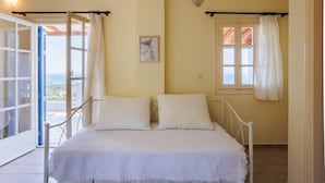 A bedroom with a bed, two pillows, a picture on the wall, and a window with curtains. - Modern Seaview Nest With Pool Panoramic Views (Kalamata)