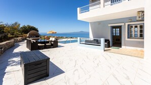 A two-story building with a balcony, outdoor seating area, and a view of the sea. - Modern Seaview Nest With Pool Panoramic Views (Kalamata)