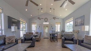 A spacious living area with leather sofas, a dining table, and ceiling fans. - Destiny's Paradise | Lux Home, Golf Cart, Private Pool (Destin)