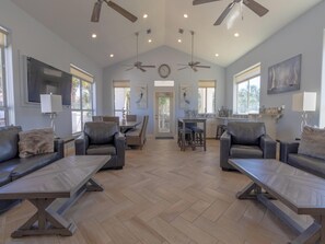 A spacious living area with leather sofas, a dining table, and ceiling fans.