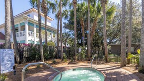 A spa pool area with a hot tub, surrounded by palm trees and a wooden fence. - Destiny's Paradise | Lux Home, Golf Cart, Private Pool (Destin)