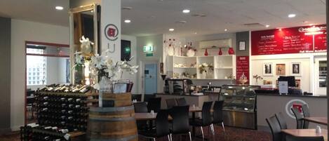 Un restaurante con zona de bar, estanterías con vino y una barra con opciones de menú.