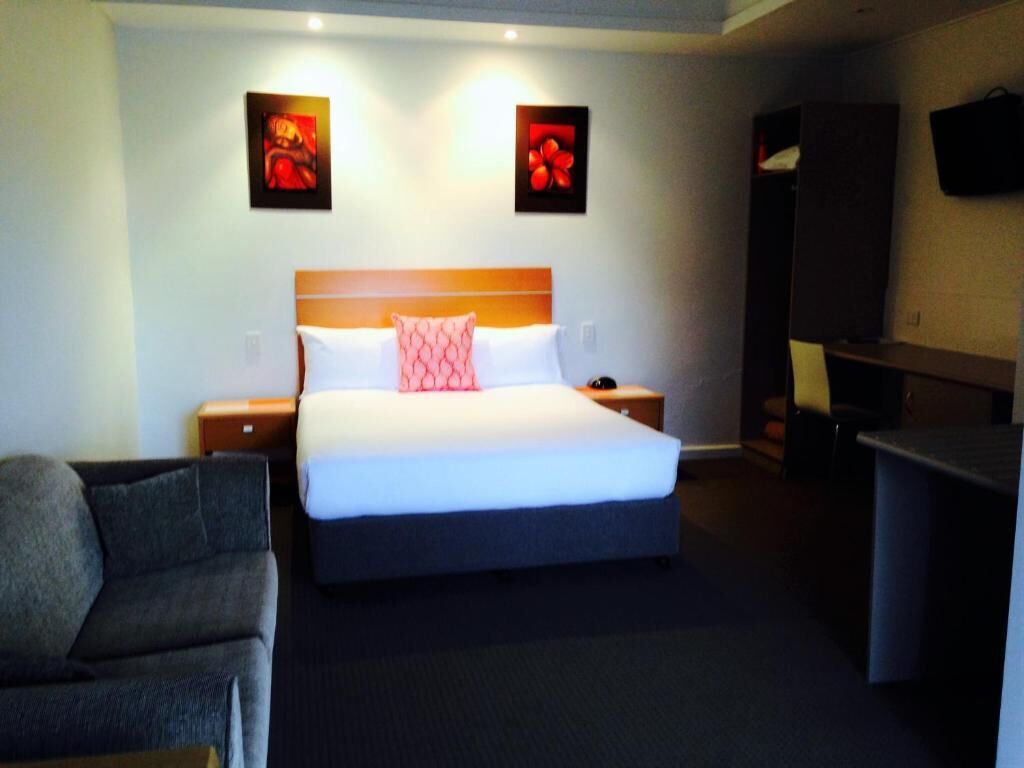 Habitación de hotel con una cama grande, una mesita de noche, un escritorio y una silla.