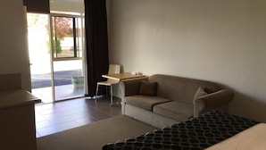 Una habitación de hotel con sofá, una mesita y una colcha estampada.
