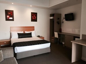 A hotel room with a bed, a desk, a chair, and a television. - Burkes Hotel Motel (Yarrawonga)