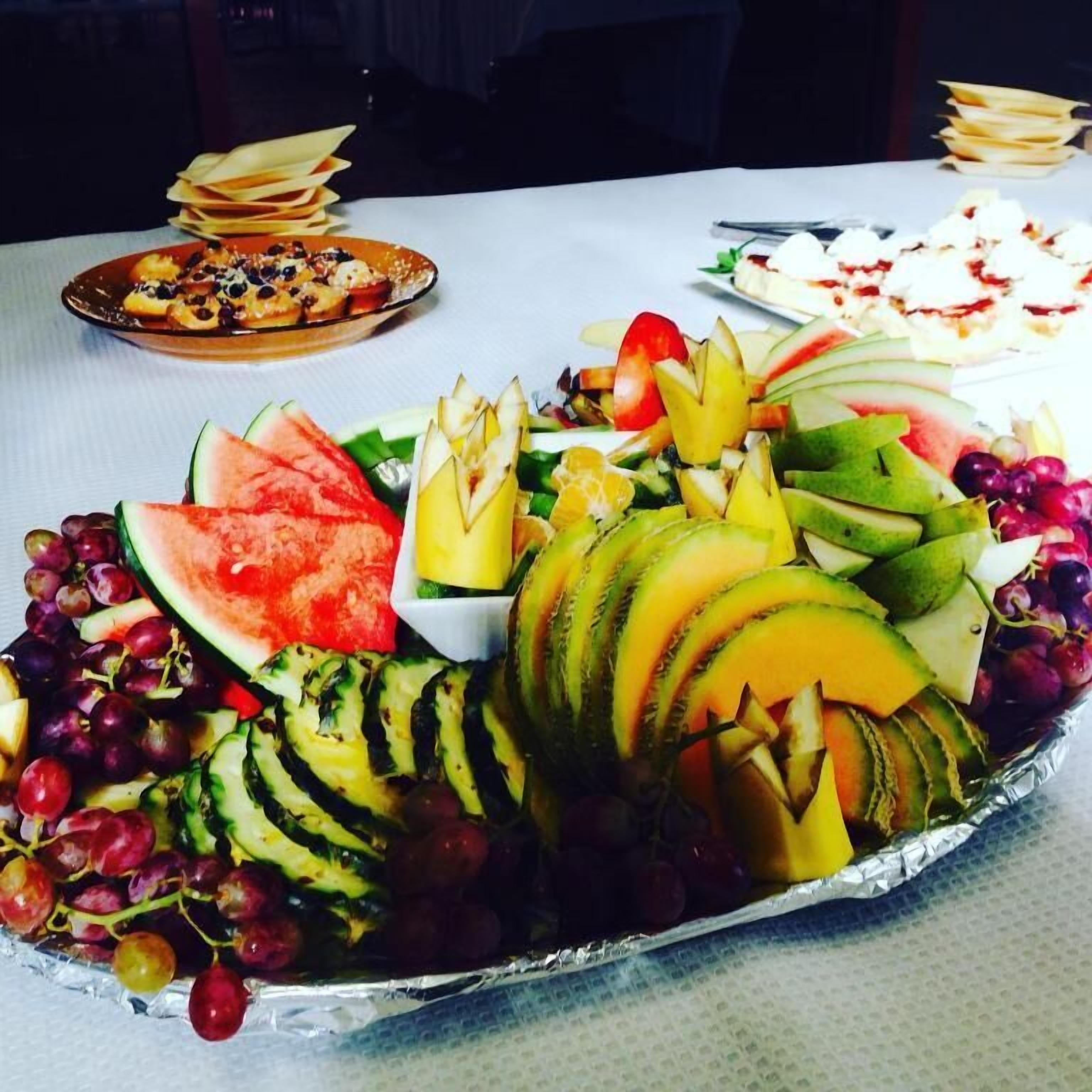 Una mesa con diversas frutas y un postre.