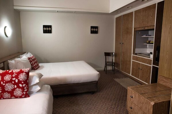Habitación de hotel con dos camas, un armario de madera, una silla y lámparas fijadas a la pared.