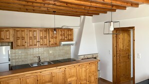 A kitchen with wooden cabinets, a tiled backsplash, a built-in stove, and a dining area with a table and chairs. - LINA'S HOUSE (Mykonos)