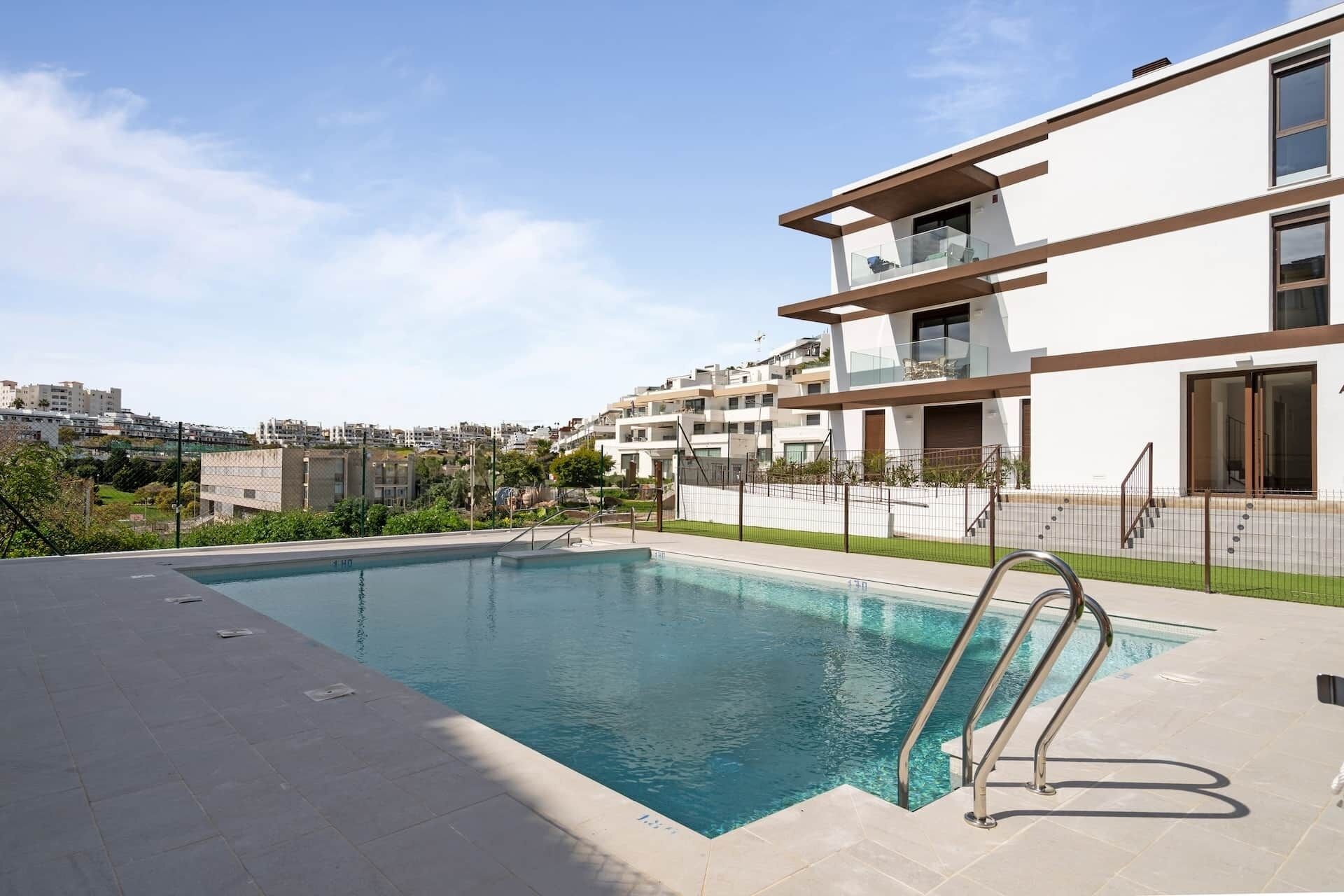 A modern residential building with a swimming pool, a balcony, and a view of the surrounding neighborhood.