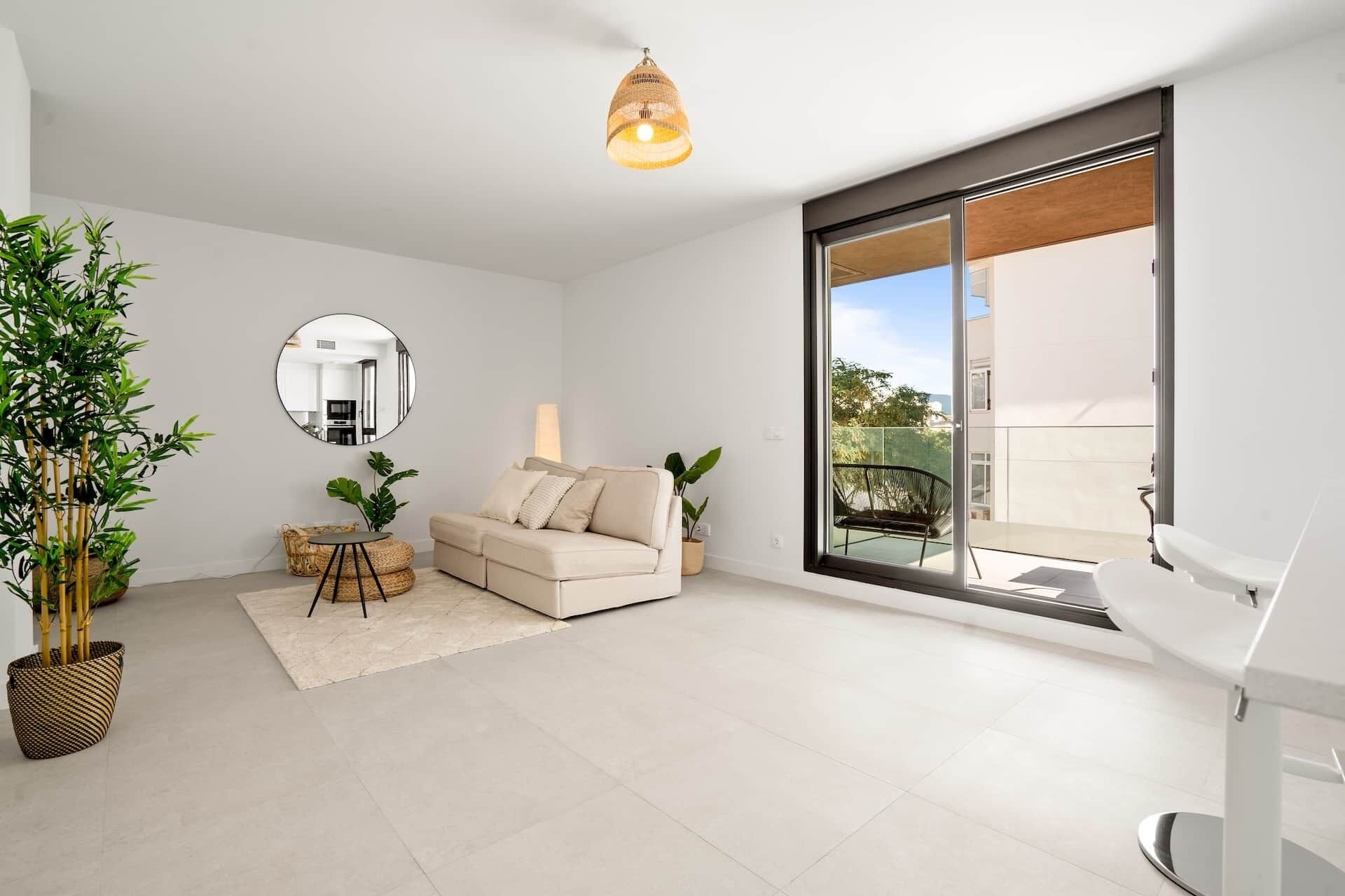 Un salon moderne avec un canapé, un miroir rond et un coin repas comprenant une table et des chaises.