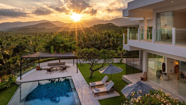 Ein modernes Haus mit Pool, Gartenmöbeln und Bergblick.