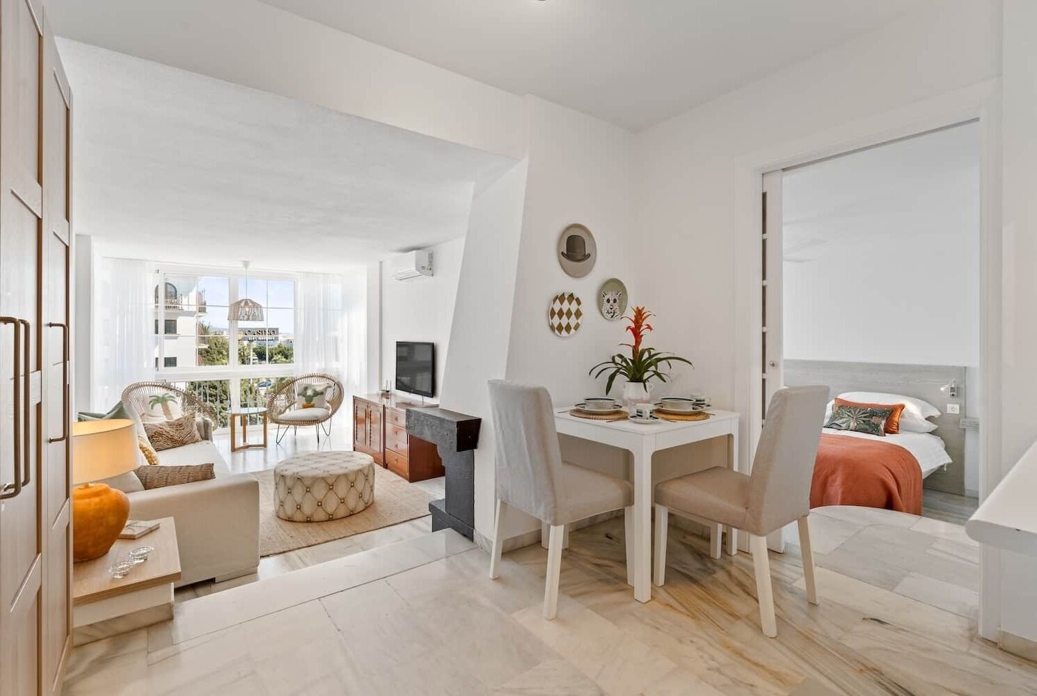 En moderne, lys stue med spiseplads, sofa og fjernsyn.