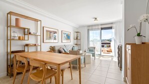 A modern living room with a wooden dining table, sofas, and a balcony with a view. - RDR487 - Modern Duplex Penthouse in gated complex (Estepona)