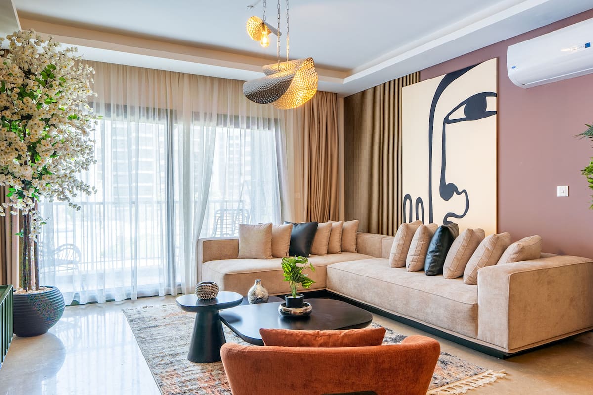 A modern living room with a beige sofa, a coffee table, and a large abstract painting on the wall.