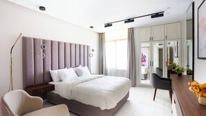 Ein modernes Schlafzimmer mit einem großen Bett, einem Nachttisch, einem Sessel und einem Schreibtisch mit einer Blumenvase.