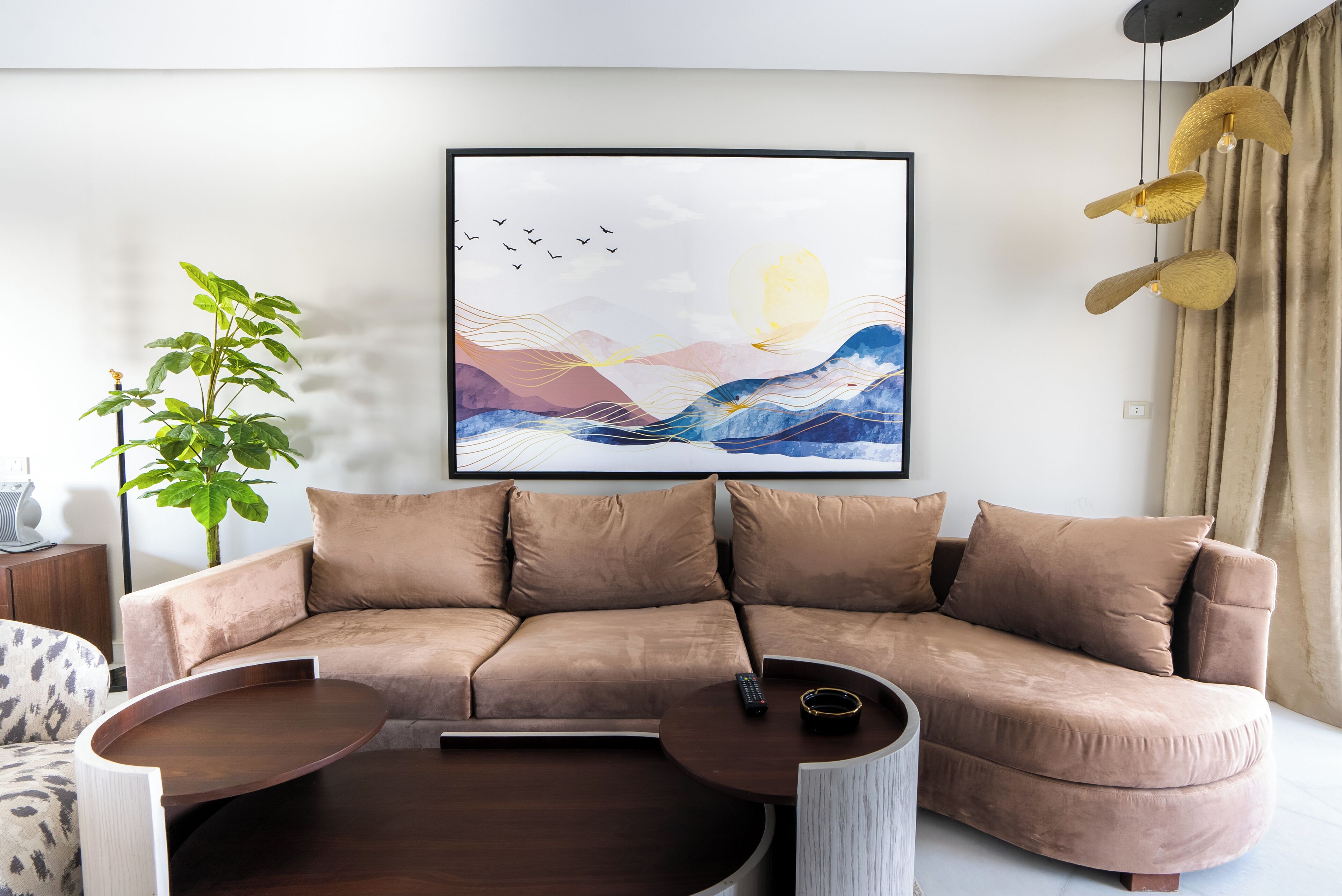 Una sala de estar moderna con un sofá color beige, una mesa de centro redonda y un cuadro abstracto enmarcado en la pared.