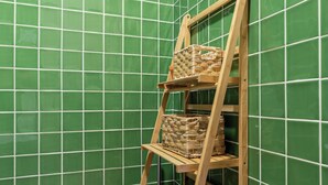A corner with a wooden ladder shelf against a green tiled wall, holding woven baskets. - Dorigem Rooms (Room 2- Twin Room) (Casal de Loivos)