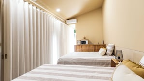 A hotel room with two beds, a wooden nightstand, a microwave, and a small table with a lamp. - Dorigem Rooms (Room 2- Twin Room) (Casal de Loivos)