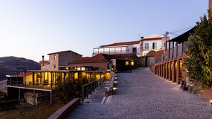 A modern building with a glass facade, a stone pathway leading to the entrance, and a hillside in the background. - Dorigem Rooms (Room 2- Twin Room) (Casal de Loivos)
